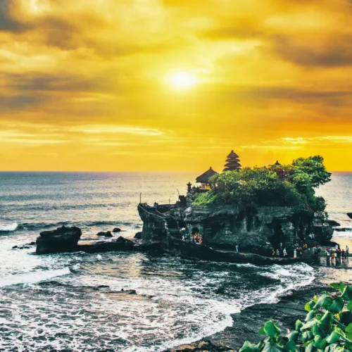 Silhouette of the sacred Tanah Lot Temple built on a rock formation in the ocean during a golden sunset.