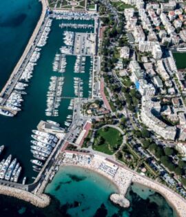 Sleek white luxury yacht moored in the vibrant Cannes marina near La Croisette.