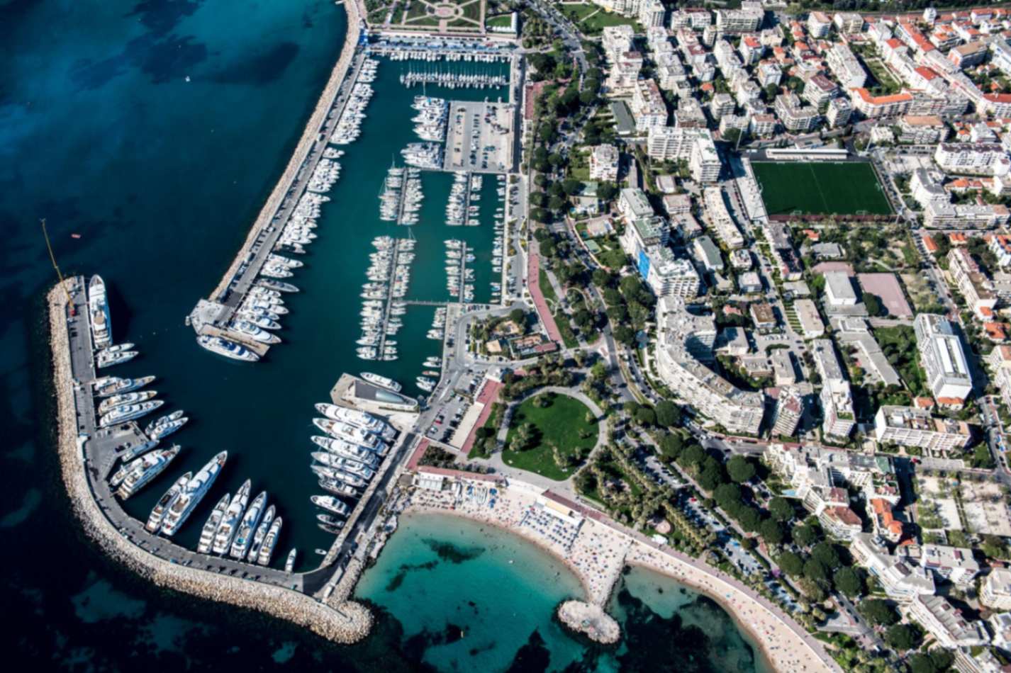 Sleek white luxury yacht moored in the vibrant Cannes marina near La Croisette.