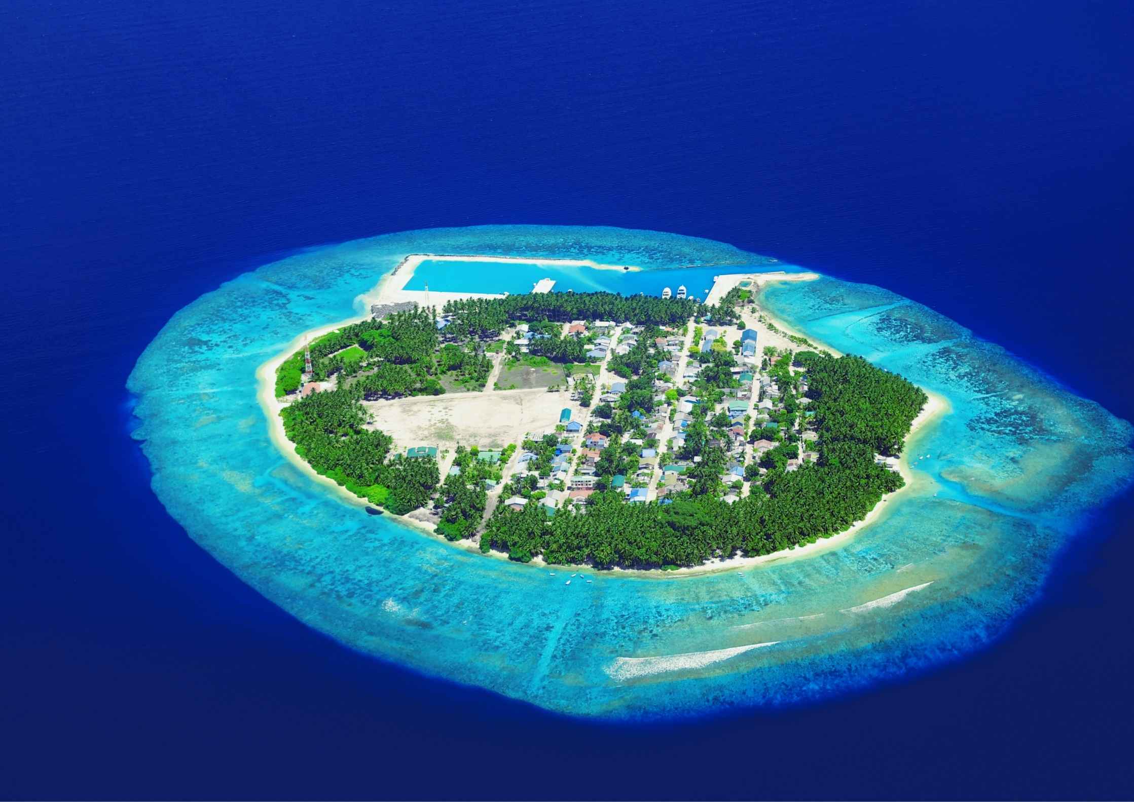 Panoramic view of a lush green island surrounded by deep blue ocean waters in the Andaman or Lakshadweep chain.