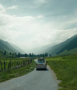 An empty, curving highway stretching through a vast, scenic valley toward distant hills.