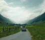 An empty, curving highway stretching through a vast, scenic valley toward distant hills.