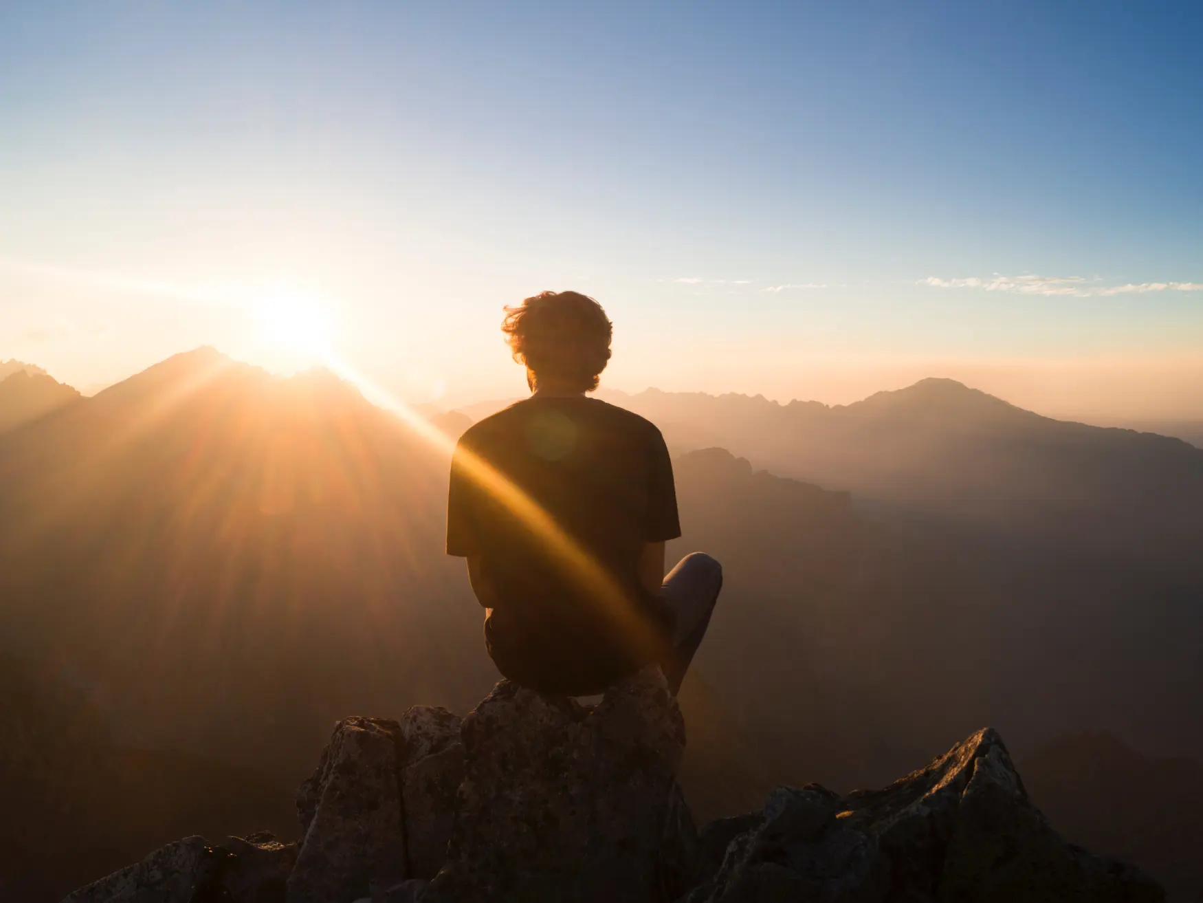 Traveller standing before misty mountain peaks at sunrise
