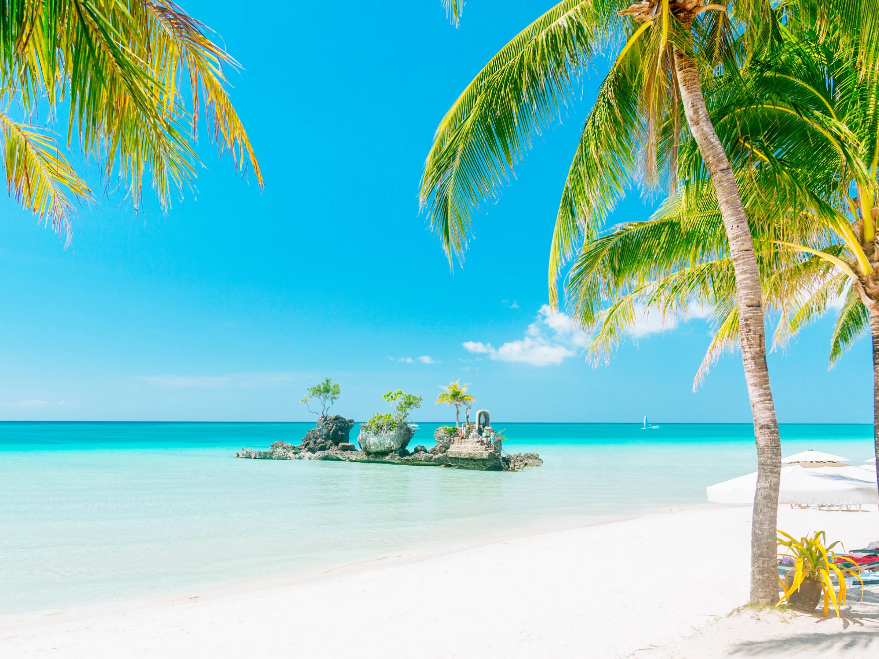 White sand and clear turquoise water framed by palm trees at Boracay, Philippines