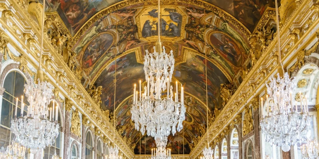 Gilded chandeliers and baroque architecture inside the Hall of Mirrors at Palace of Versailles.