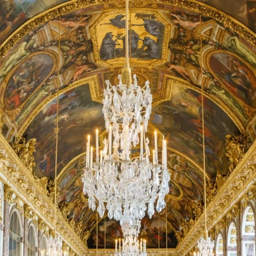 Gilded chandeliers and baroque architecture inside the Hall of Mirrors at Palace of Versailles.