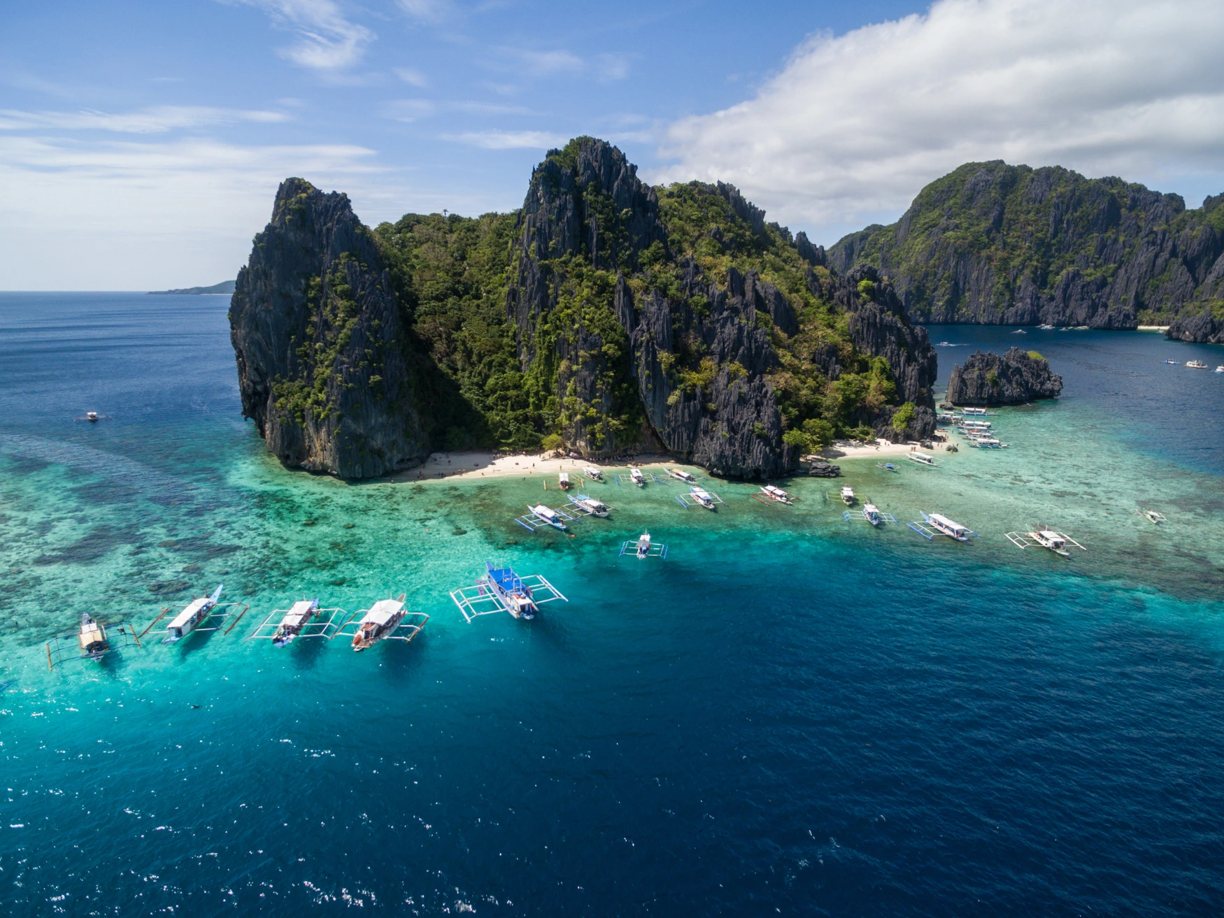Turquoise sea, boats and dramatic limestone cliffs in El Nido, Palawan