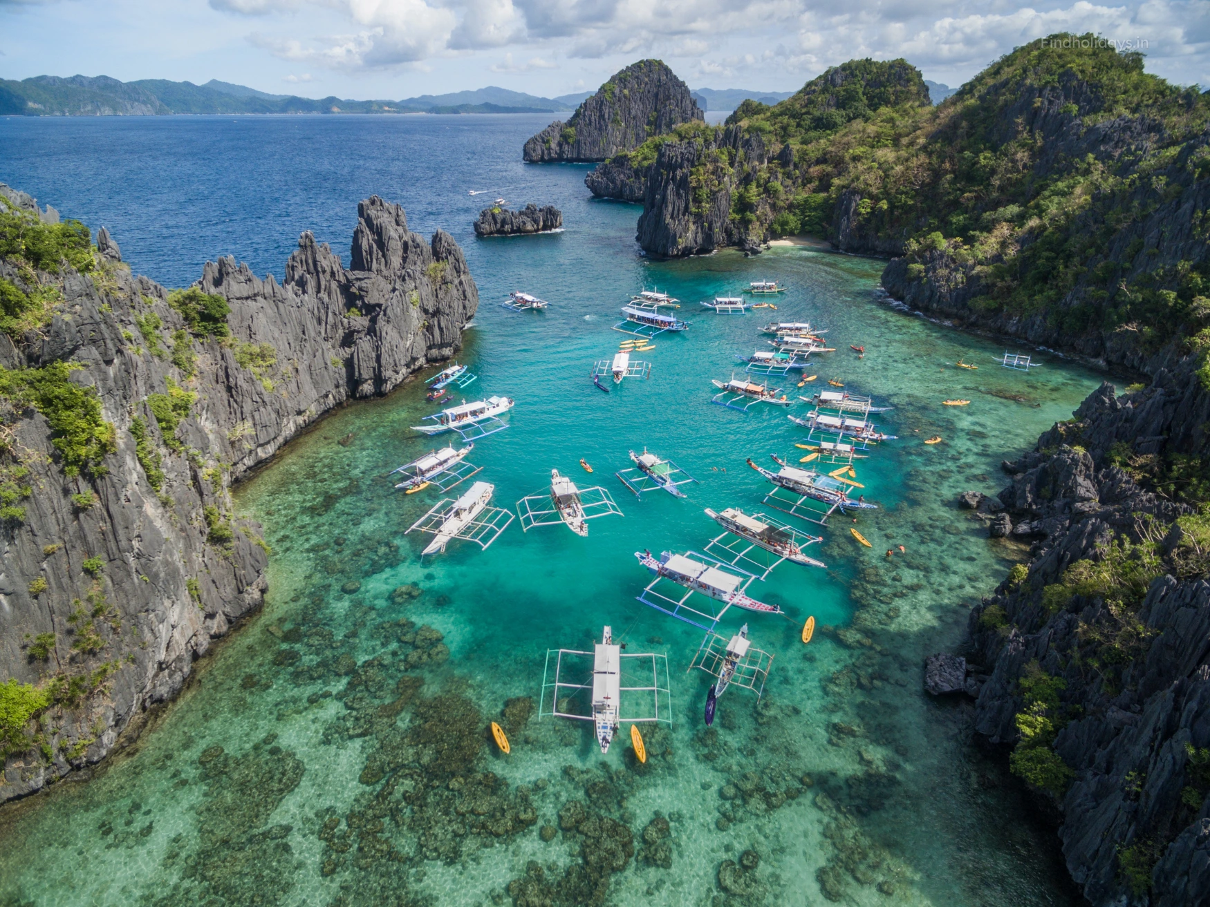 Aerial view of turquoise water, limestone cliffs and island-hopping boats in Palawan, Philippines